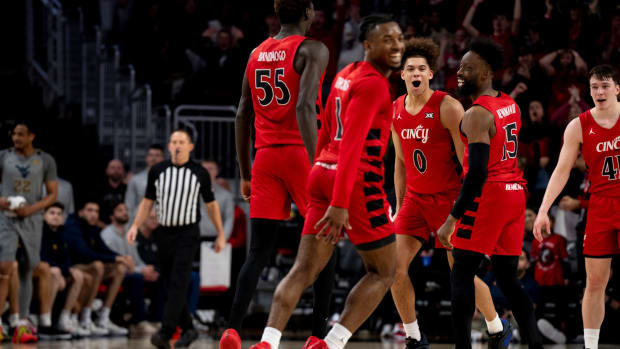 Cincinnati Bearcats guard Dan Skillings Jr. (0) and Cincinnati Bearcats forward John Newman III (15) react after Cincinnati Bearcats guard Day Day Thomas (1) scored on a dunk in the second half of the NCAA basketball game between Cincinnati Bearcats and West Virginia Mountaineers at Fifth Third Arena in Cincinnati on Saturday, March 9, 2024.